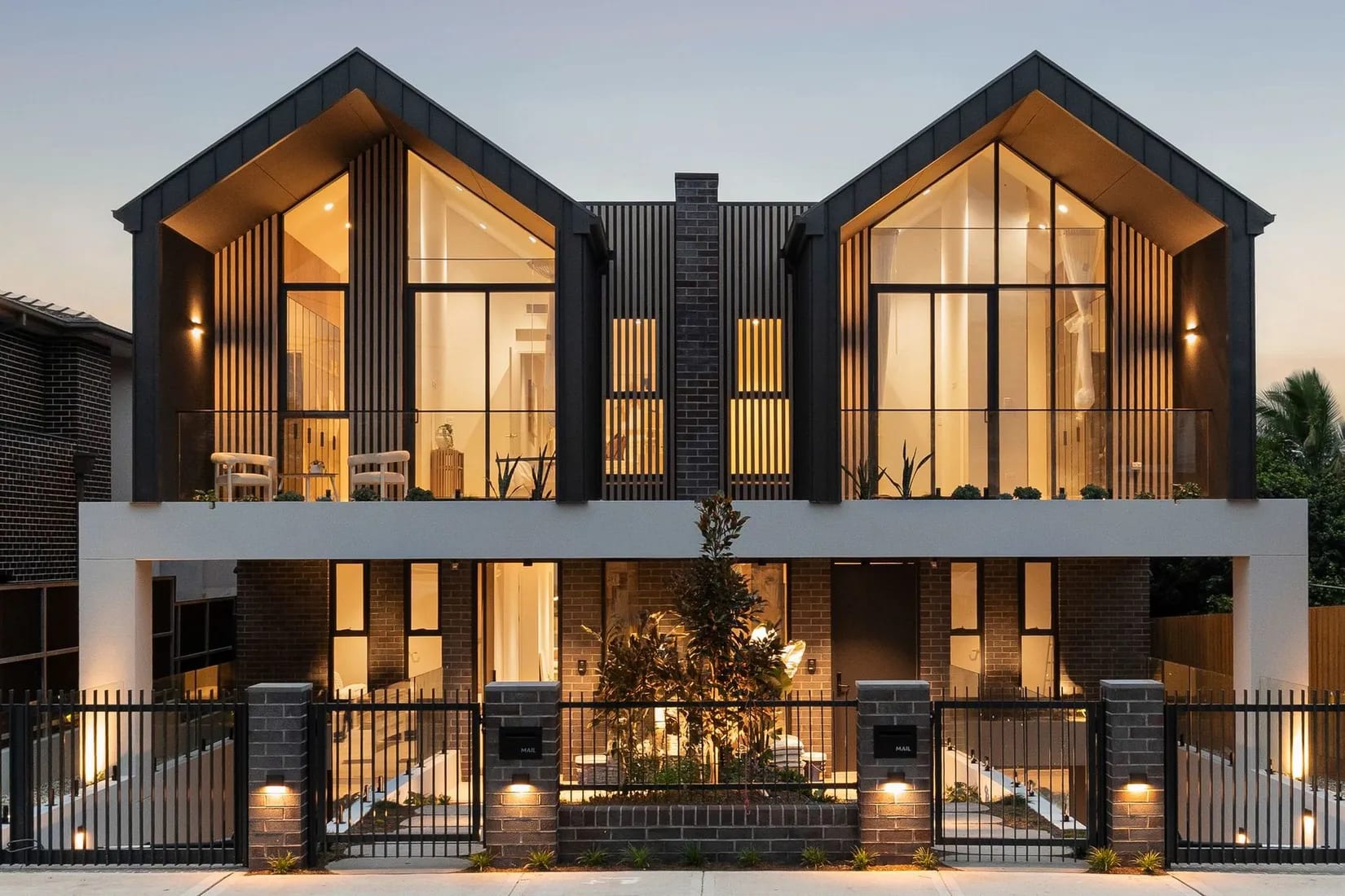 Burwood duplex at twilight — timber-look aluminium battens framing the gable windows above vertical batten screens