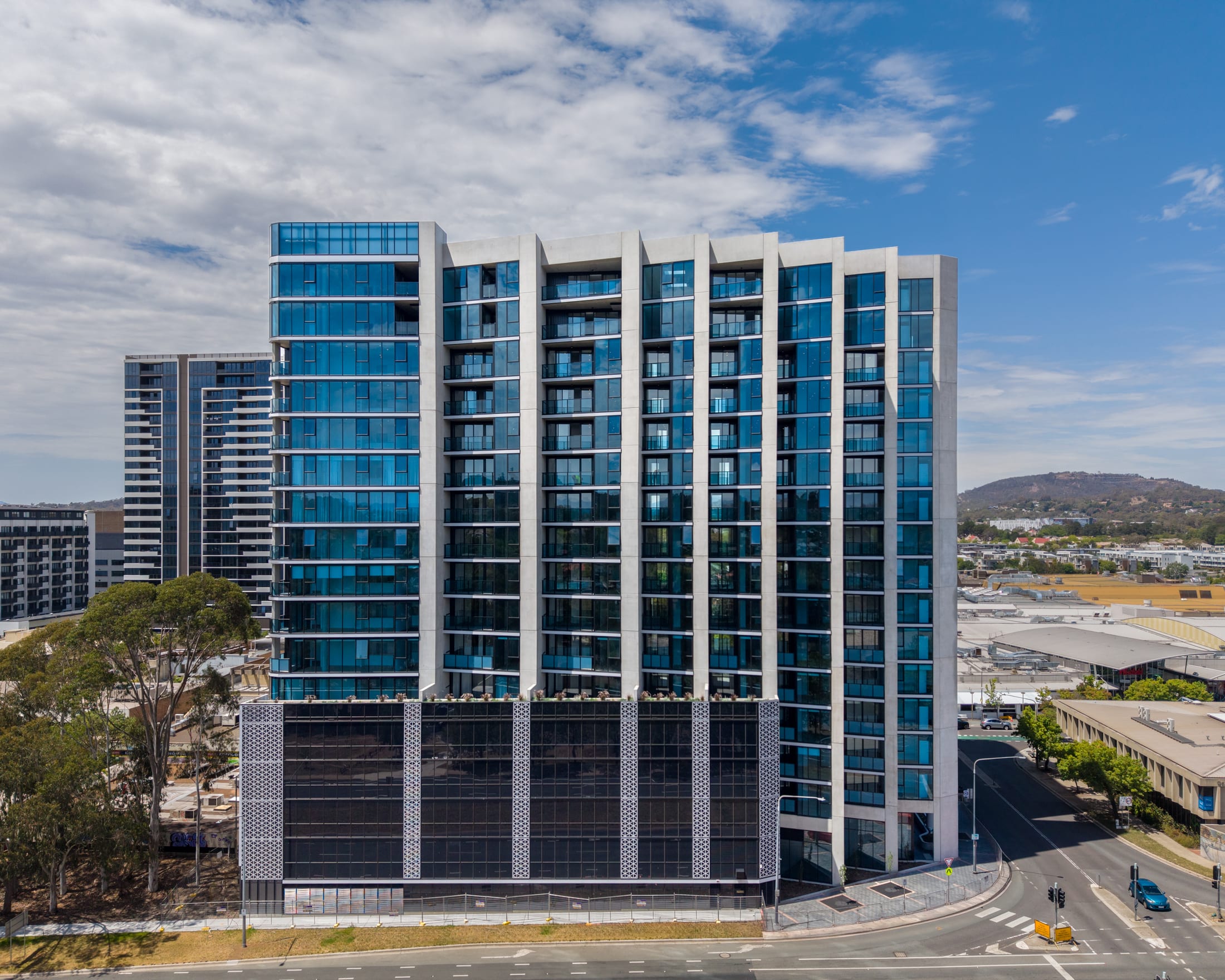 Woden, Canberra — residential tower with aluminium batten screens above a perforated podium against the Canberra hills